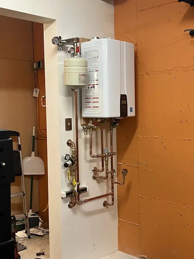 Plumbing technician inspecting water heater connections in Fuquay